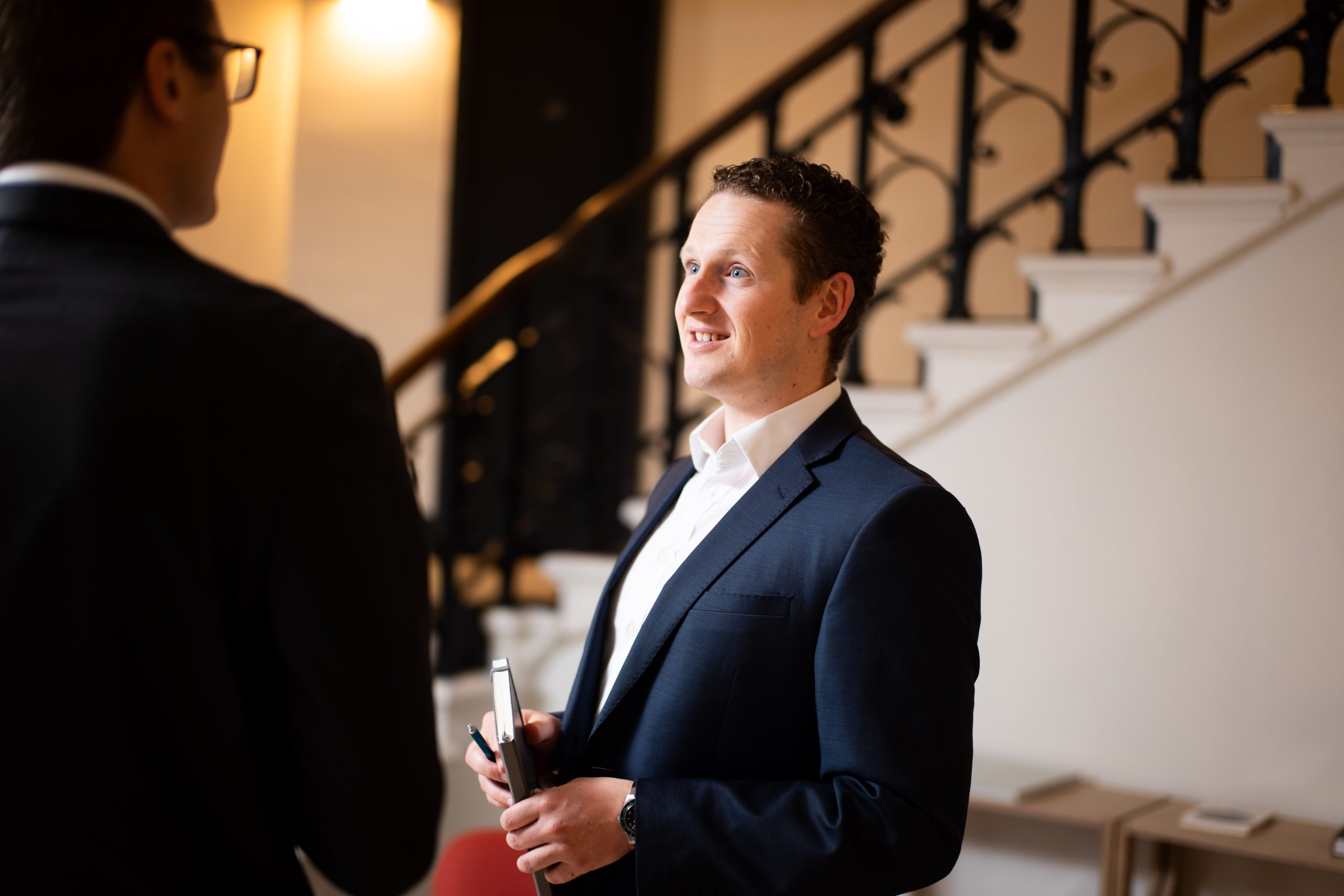 How we work - A man in a suit holding a tablet and a pen.