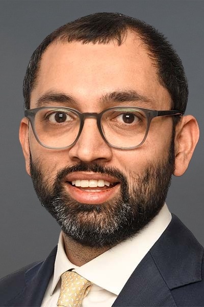 Varun Khanna, a man with glasses and a beard, is posing for a photo.