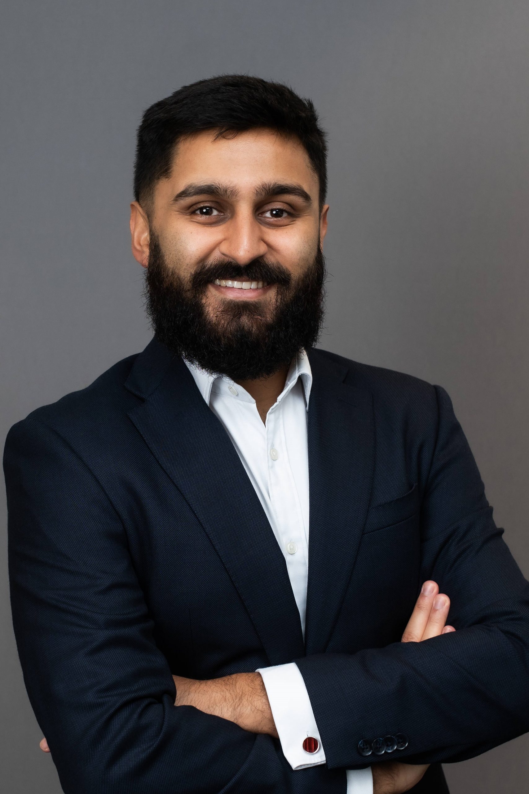 A bearded man, Ujwal Thapa, in a suit posing for a photo.
